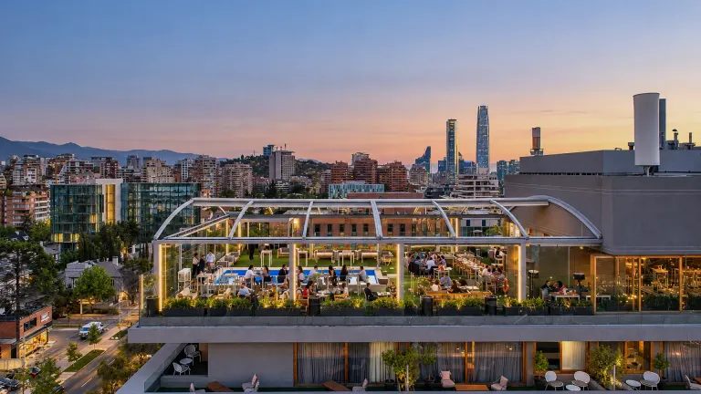 Pérgola retráctil PergoDom sobre el rooftop de un hotel al atardecer, con la ciudad al fondo