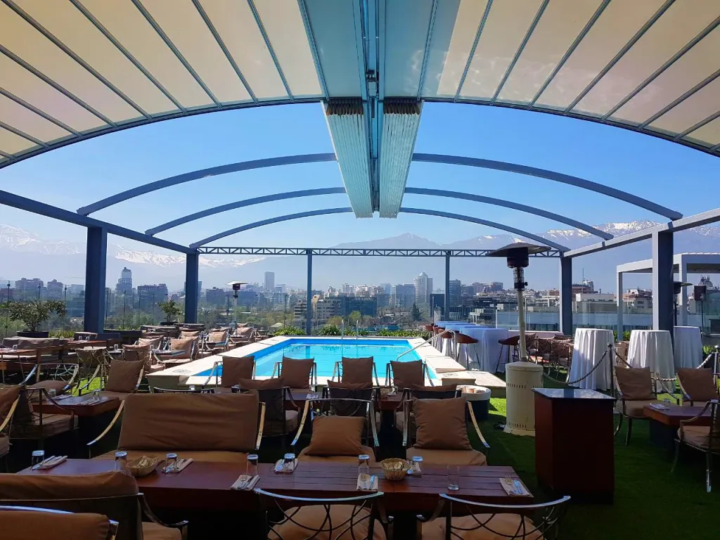 Pérgola retráctil PergoDom sobre el comedor junto a la piscina del rooftop del hotel Noi