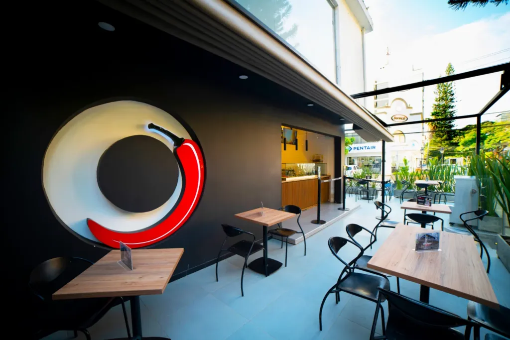 Mesas de la terraza del Chilitaco con la pérgola PergoFlex abierta hacia la calle