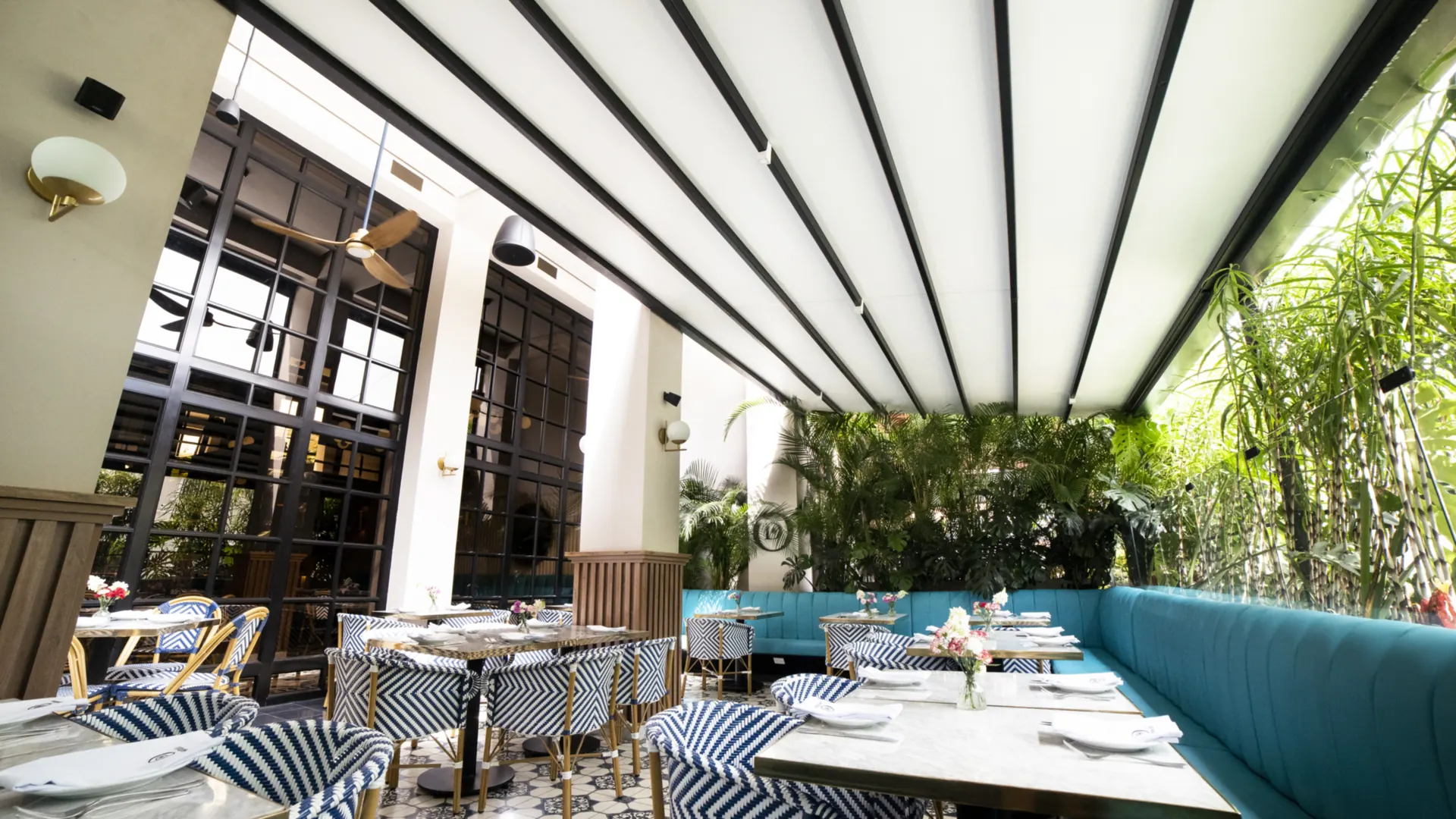 Pérgola retráctil PergoFlex extendida sobre el salón de Odiseo, entre la fachada y la vegetación