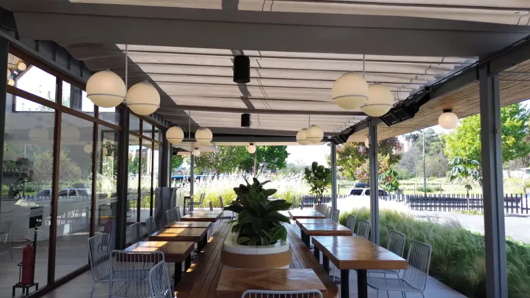Pérgola retráctil Pergolite sobre la terraza de mesas largas de Home Burger en Bogotá