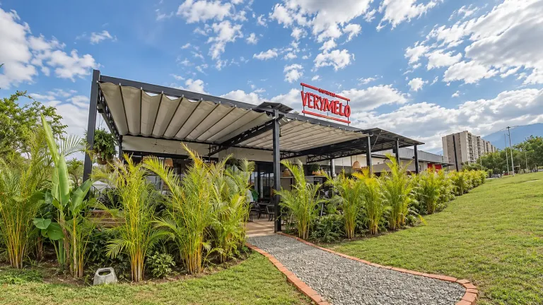 Pérgolas Pergolite con lona plegada sobre la terraza del gastrobar Verymelo en Cali, rodeadas de jardín