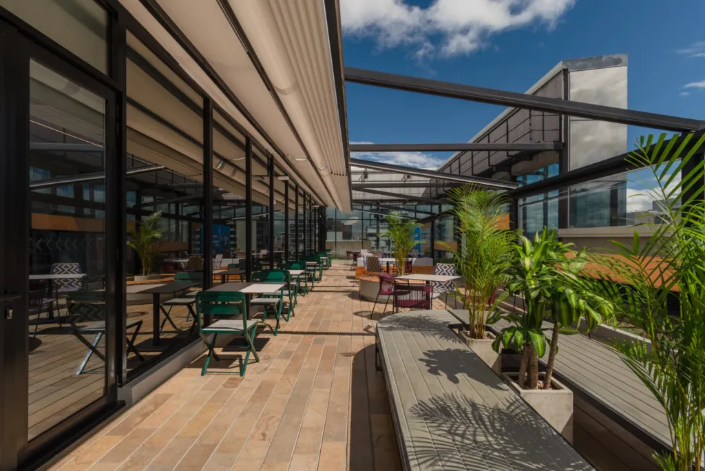 Pérgola retráctil PergoTek sobre el corredor de mesas de una terraza en La Roche