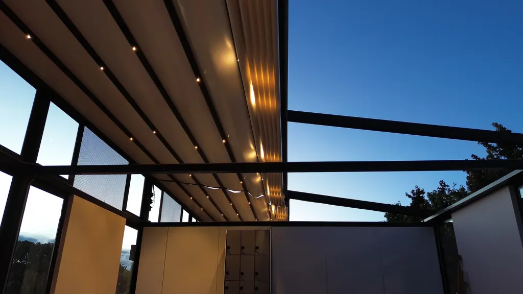 Pérgola retráctil parcialmente abierta con LED junto a la fachada de vidrio de la Universidad de La Sabana
