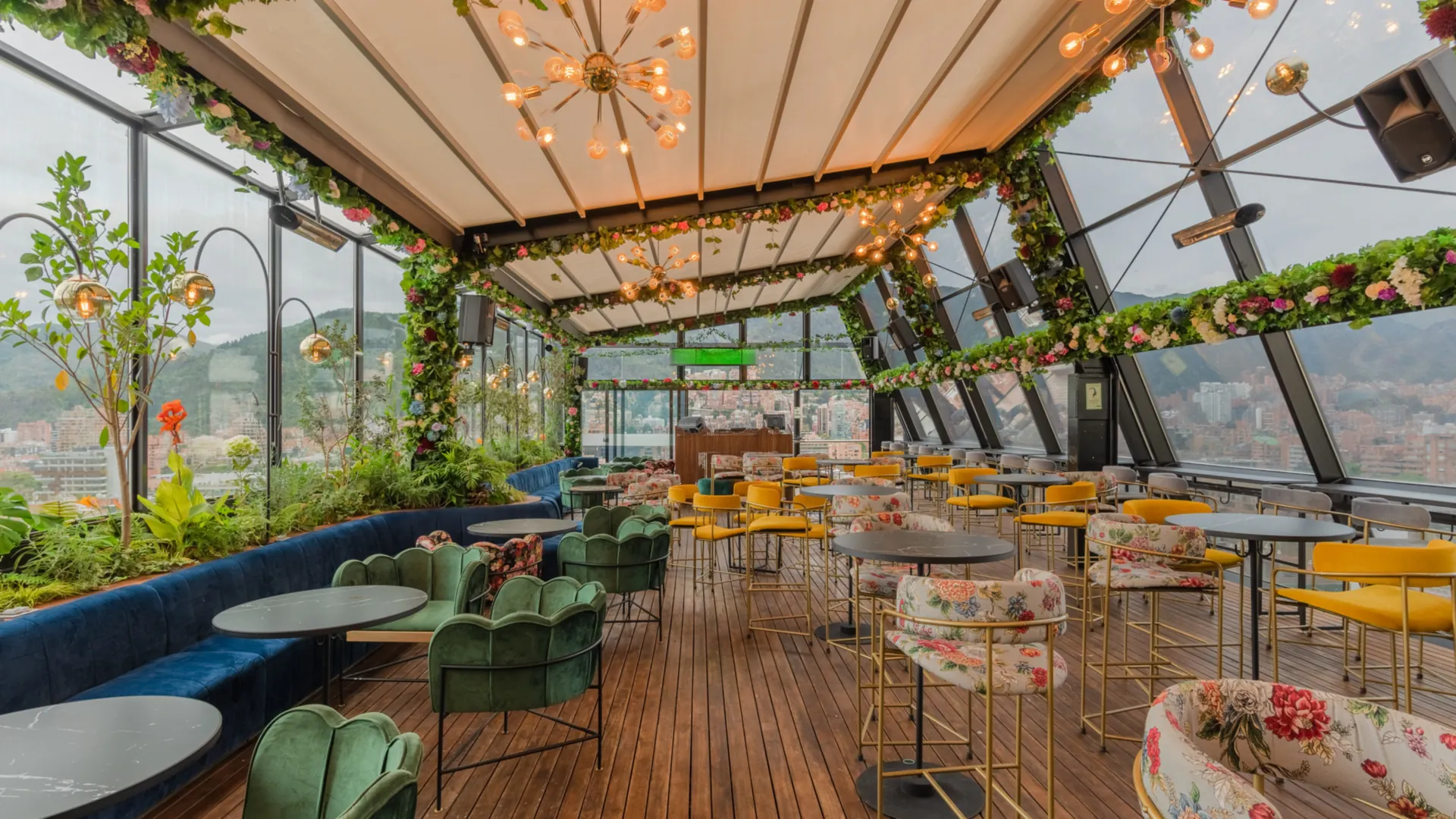 Pérgola retráctil PergoTek cerrada sobre el salón de Mónaco Rooftop, con lámparas y guirnaldas de flores