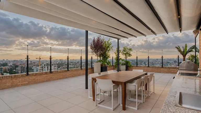 Pérgola retráctil PergoTek Romano sobre una terraza con comedor exterior al atardecer
