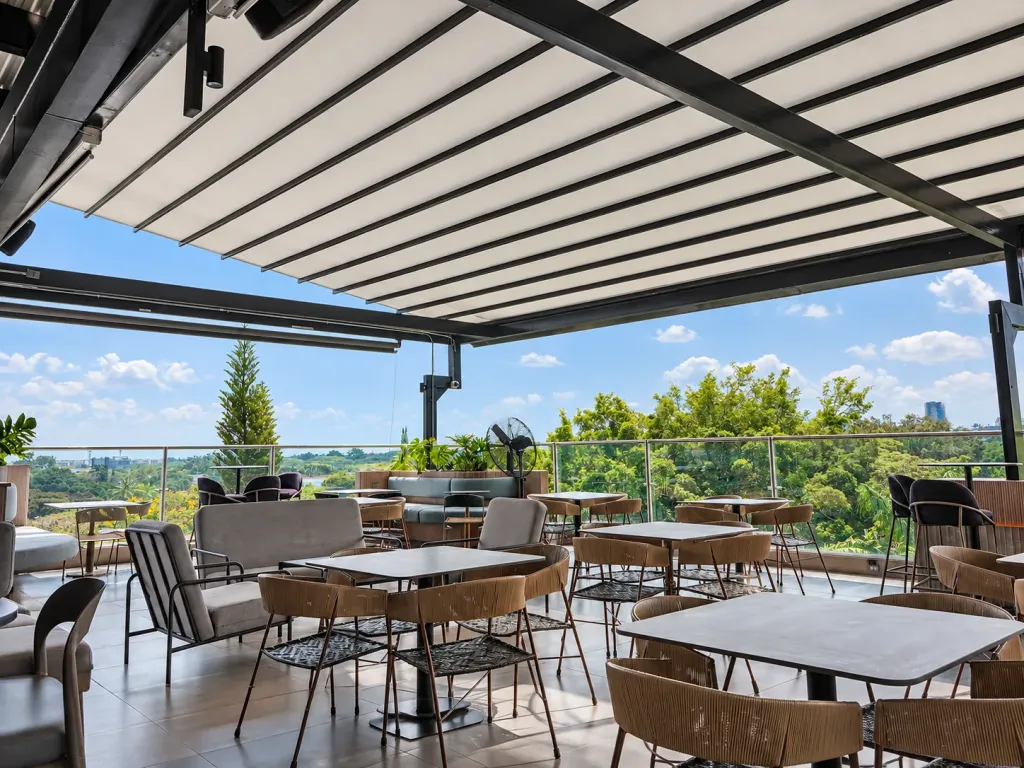 Mesas y sillas de fibra bajo la lona de la pérgola PergoTek en el rooftop de Sabor Molido, Cali