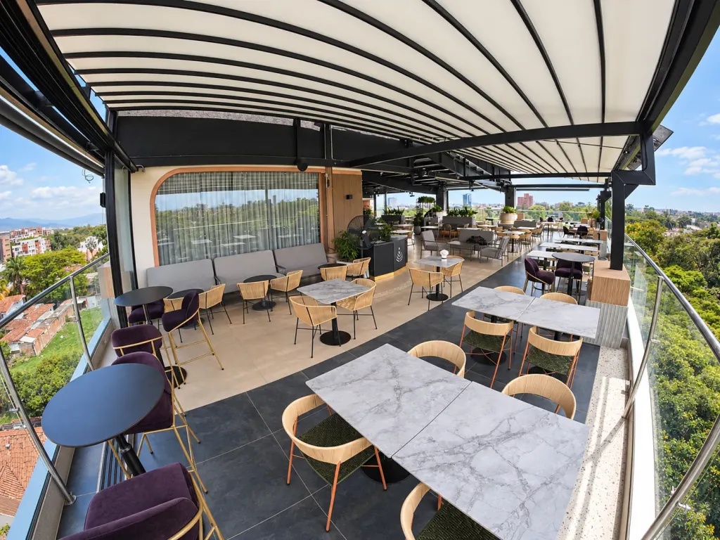 Terraza lateral de Sabor Molido cubierta por la pérgola PergoTek junto a la baranda de vidrio