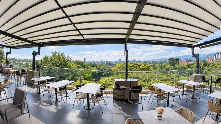 Pérgola PergoTek cerrada sobre el rooftop de Sabor Molido en Cali con vista a la vegetación y la ciudad