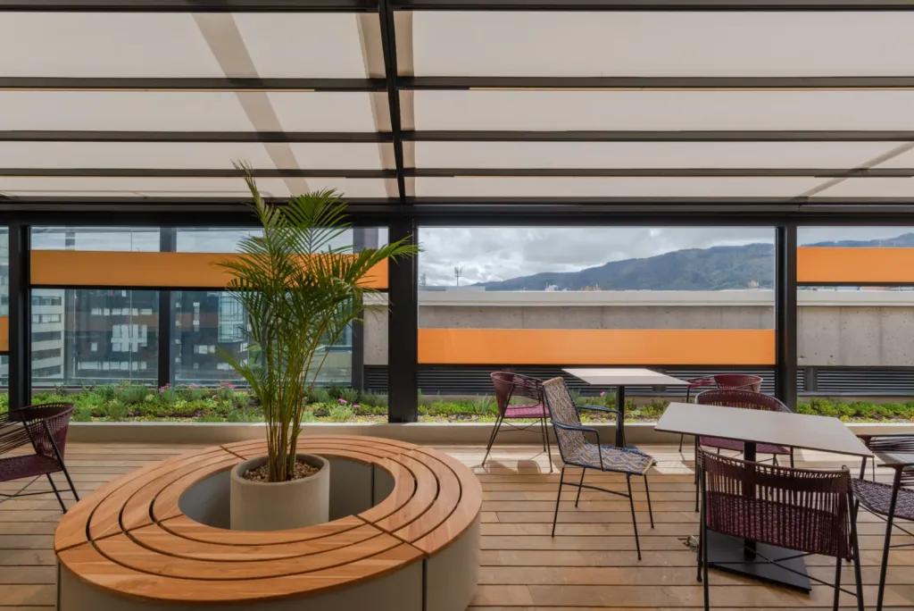 Pérgola retráctil PergoTek sobre la terraza de La Roche, con banca circular de madera y palma