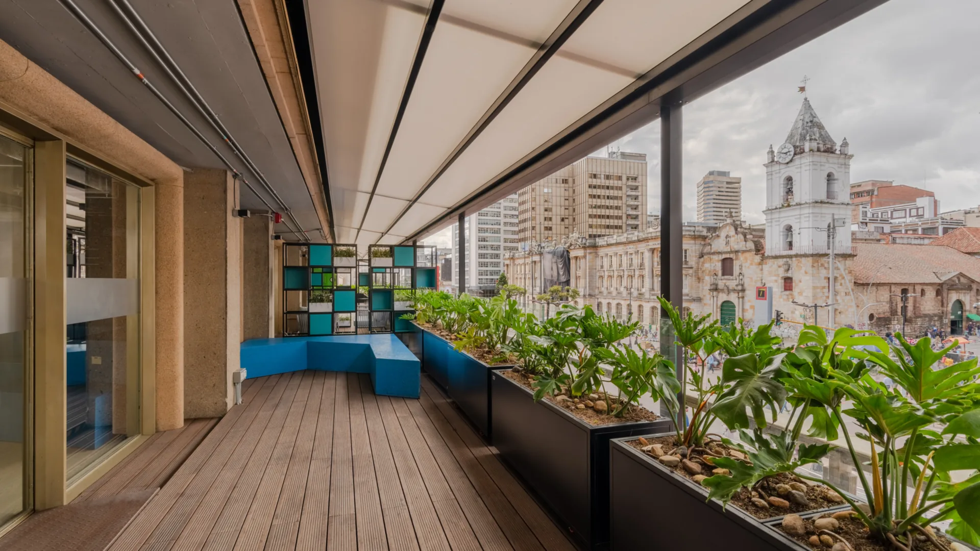 Pérgola retráctil PergoTek cerrada sobre la terraza larga con jardineras del Edificio El Tiempo en Bogotá