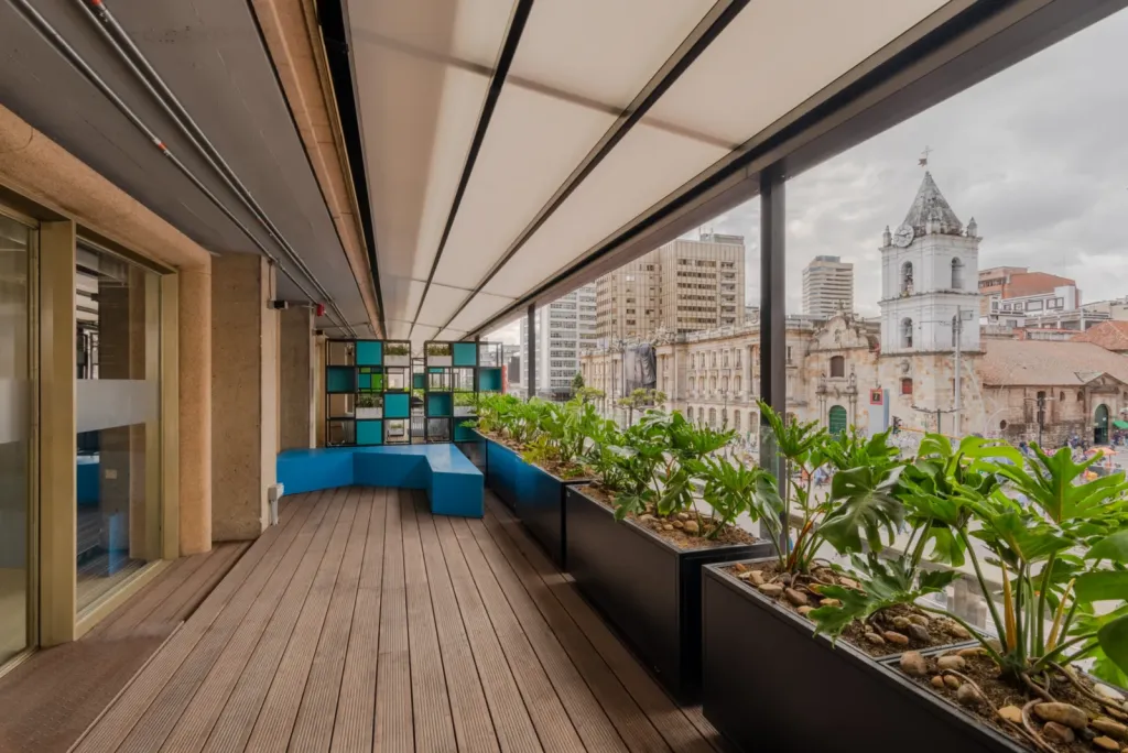 Pérgola retráctil PergoTek sobre la terraza del Edificio El Tiempo, con jardineras frente a una iglesia del centro de Bogotá