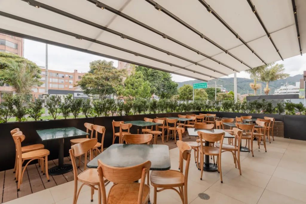 Pérgola retráctil PergoTek sobre el comedor exterior de un restaurante El Corral, con los cerros al fondo