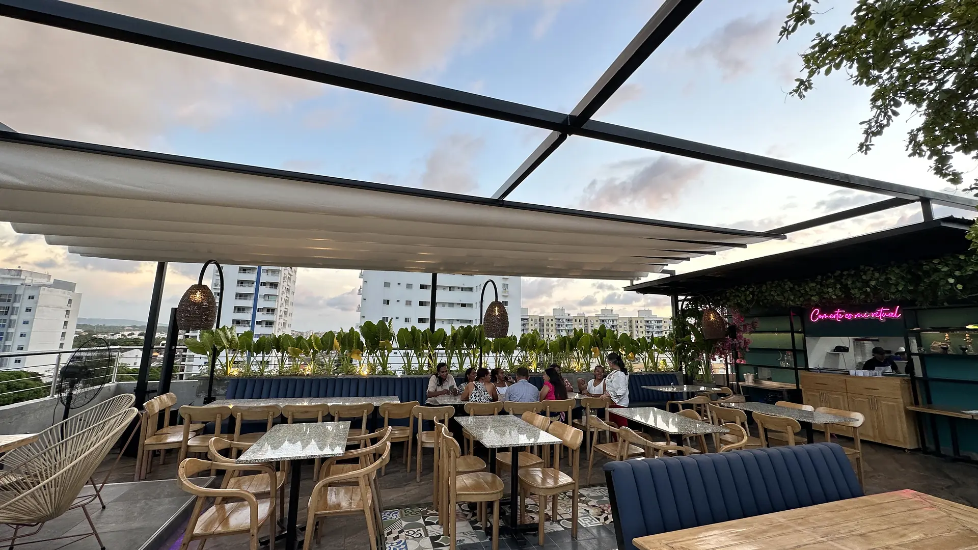 Pérgola retráctil PergoTek de lona blanca sobre la terraza en azotea del restaurante Ritual al atardecer