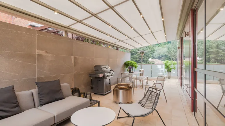 Pérgola retráctil PergoTek sobre la terraza de un apartamento con sala exterior y asador, en el Edificio Icon Cabrera de Bogotá