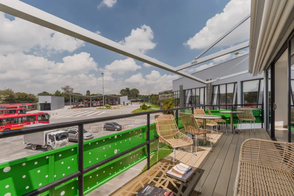 Terraza del Portal 80 de TransMilenio con la pérgola PergoTek abierta y sillas de fibra junto a la baranda