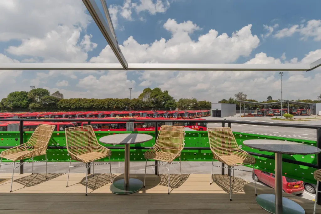 Pérgola retráctil abierta sobre mesas altas en la terraza del Portal 80 de TransMilenio
