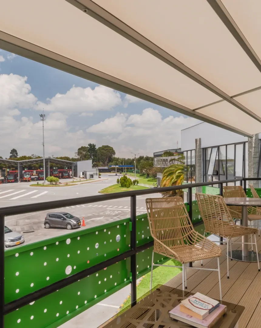 Pérgola retráctil PergoTek cerrada sobre la terraza del Portal 80 de TransMilenio, con los buses al fondo