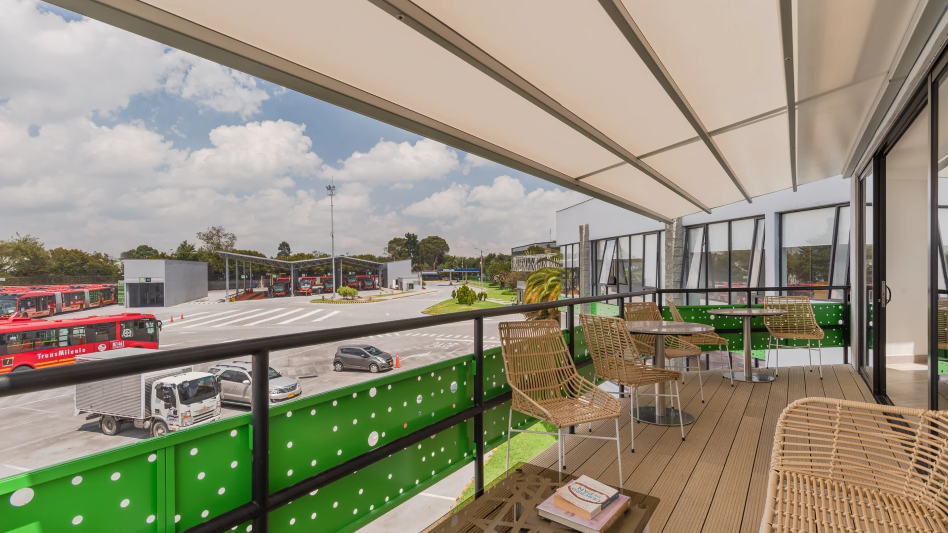 Pérgola retráctil PergoTek cerrada sobre la terraza del Portal 80 de TransMilenio, con los buses al fondo