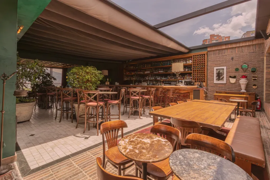 Salón de El Zarzo Bar en Medellín con la PergoTek abierta y la luz entrando sobre las mesas