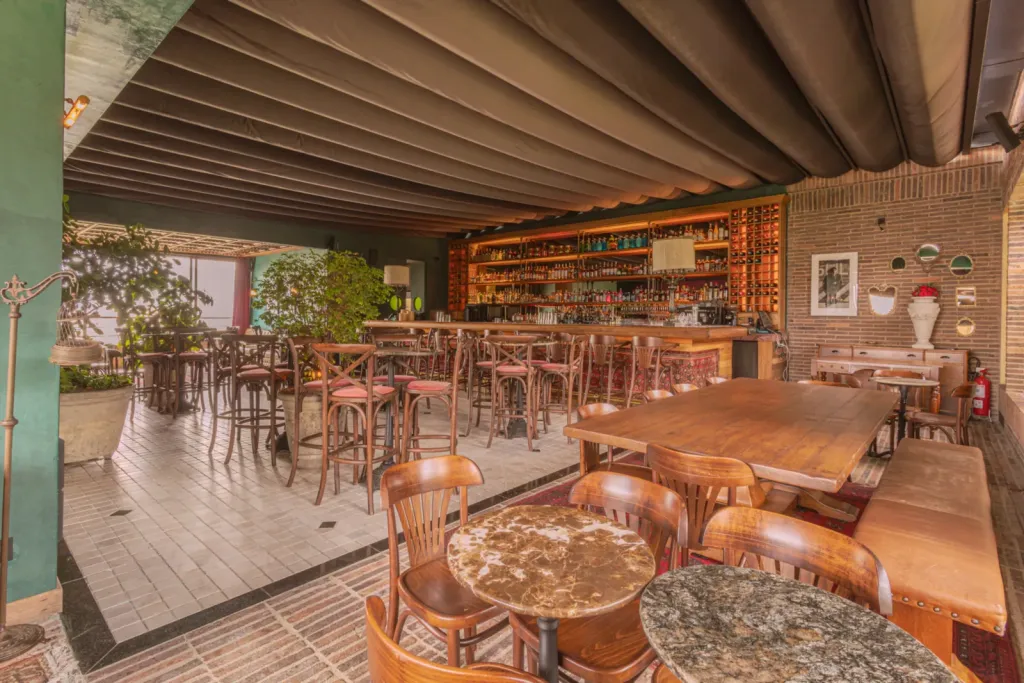 Salón de El Zarzo Bar en Medellín bajo la lona ondulada de la PergoTek cerrada