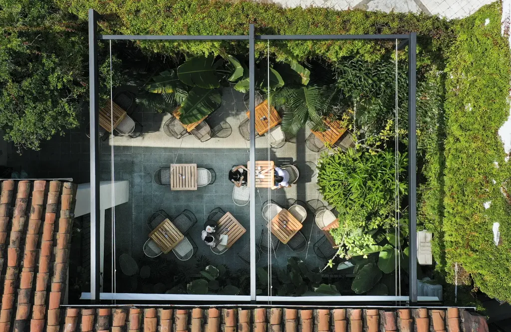 Vista aérea con la PergoFlex recogida, que deja ver la estructura de aluminio y las mesas del patio del Café Gardenia