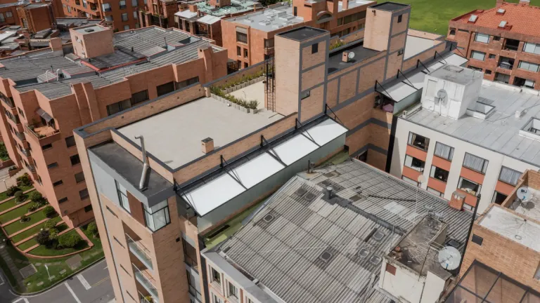 Vista aérea de la cubierta retráctil sobre la terraza en la azotea del Edificio Albatroz entre edificios de ladrillo