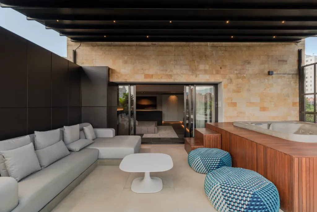 Sala exterior del ático del Edificio Atico II bajo la pérgola retráctil cerrada con luces integradas