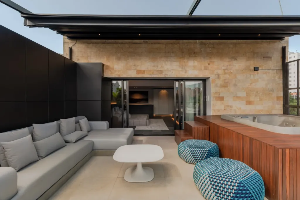 Pérgola retráctil abierta sobre la sala exterior y el jacuzzi del ático del Edificio Atico II
