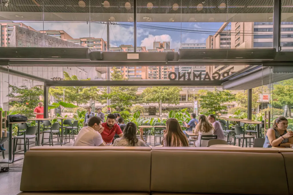 Clientes en la terraza cubierta de Pergamino Café en Medellín con cerramiento de vidrio y vista a la ciudad