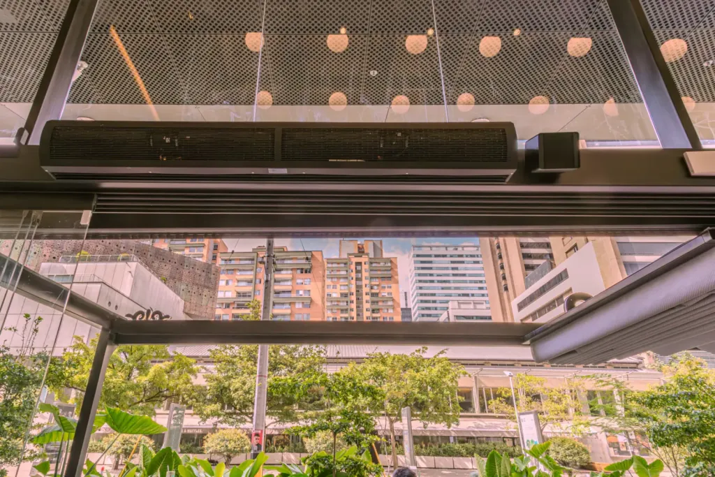 Estructura metálica de la pérgola y cortina de aire en el acceso de la terraza de Pergamino Café, Medellín