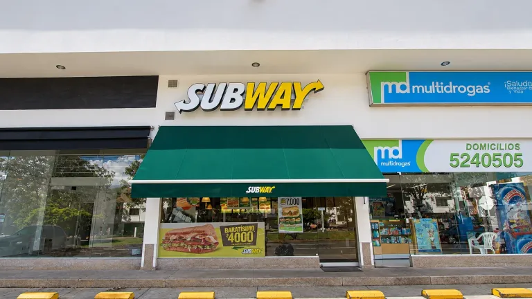Toldo de brazos proyectantes en lona verde sobre la vitrina de Subway en un local comercial de Bogotá
