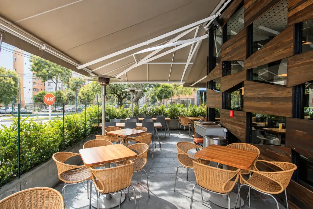 Brazos articulados del toldo retráctil sobre las mesas de mimbre de la terraza de Creppes & Waffles