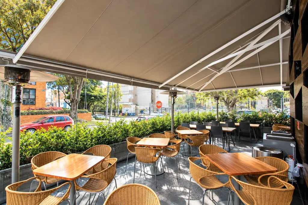 Terraza de Creppes & Waffles cubierta por el toldo retráctil de brazos, con vista hacia la calle
