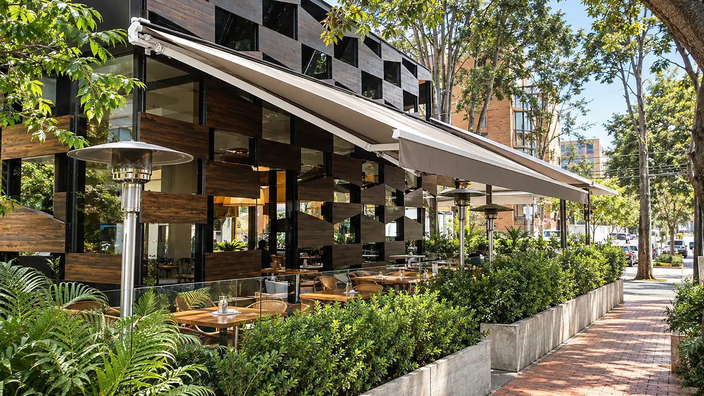 Toldo retráctil extendido sobre la terraza de Creppes & Waffles, entre jardineras y la acera de ladrillo